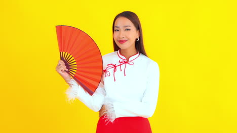 a pretty young asian woman holds a red fan