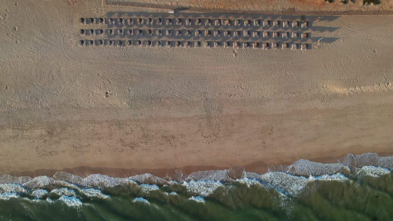 포르투갈 알가르베 의 모래 해변 에서 파도 근처 에 있는 해변 우산 의 위상