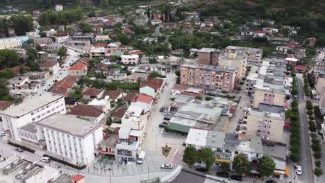vista aérea panorámica de un pueblo junto a un río, con coches circulando por las calles, albania