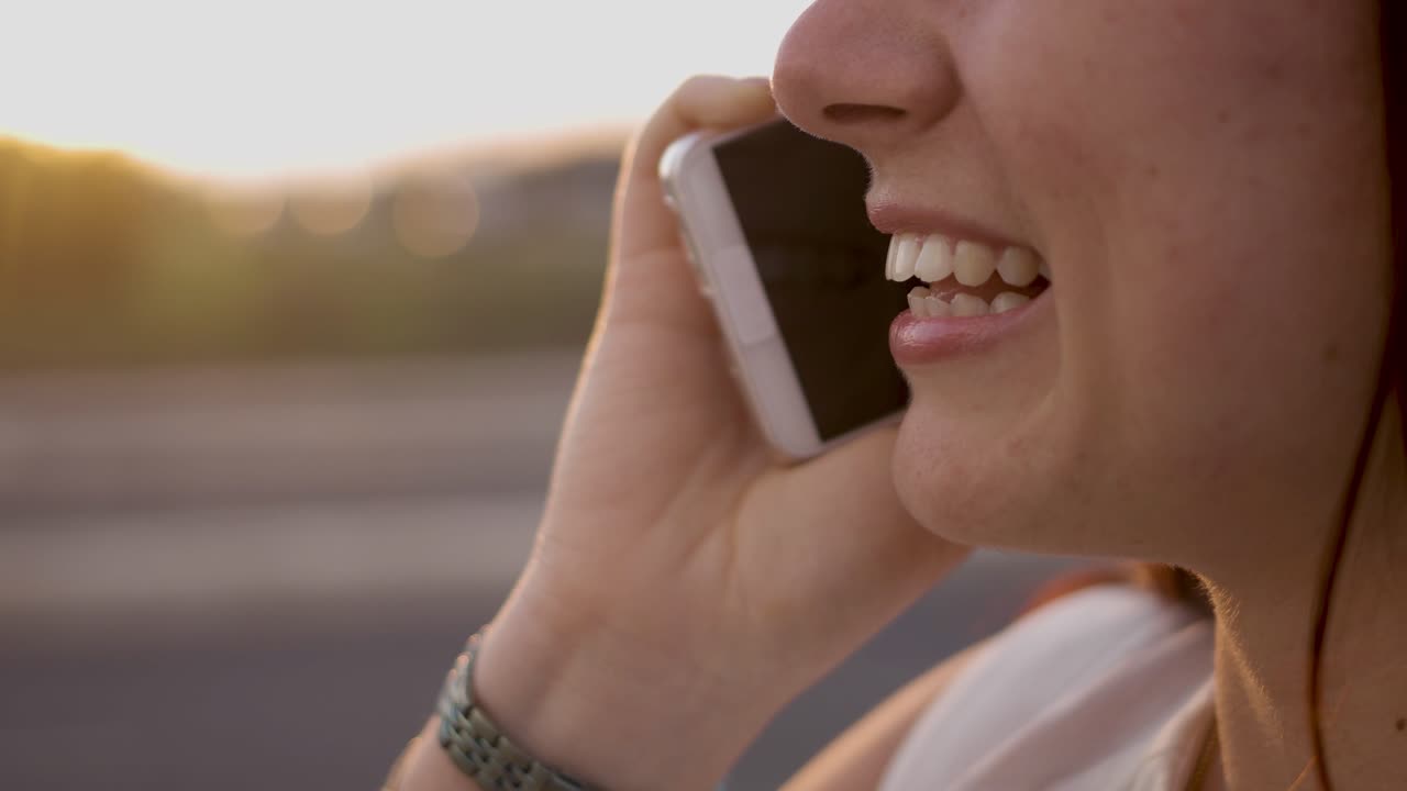 un primer plano de una mujer sonriente conversando por teléfono.
