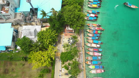 Traditional-longtail-boats-anchored-at-harbour,-Koh-Phi-Phi-Don-island,-Thailand,-aerial-top-down