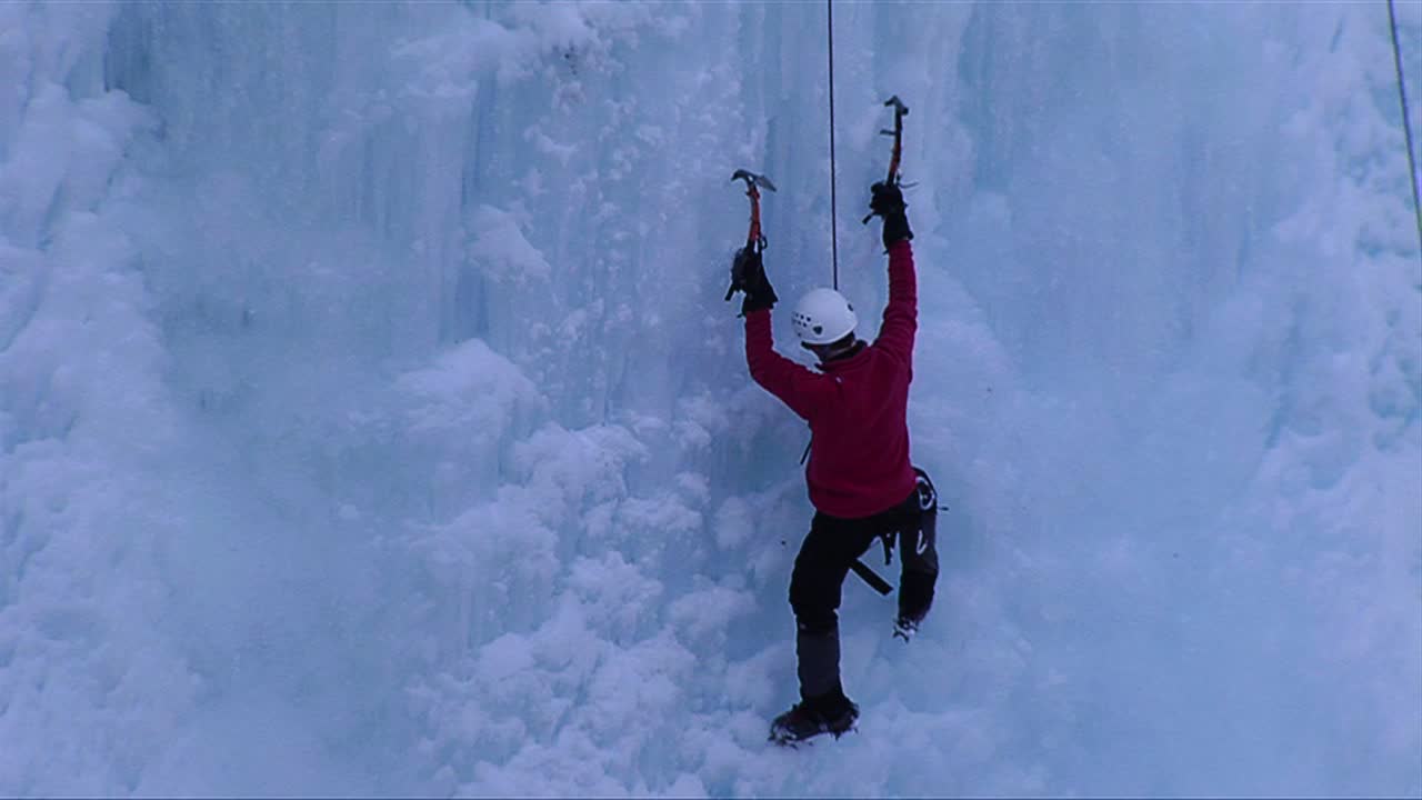 мужчина взбирается на замерзший водопад