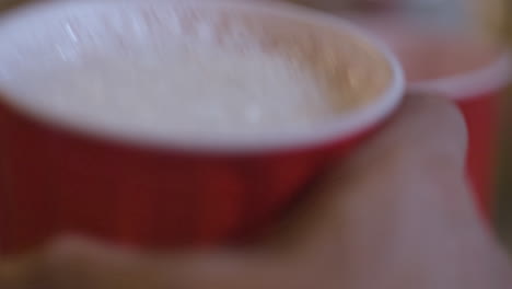 primer plano macro de una mano recogiendo una taza llena de cerveza