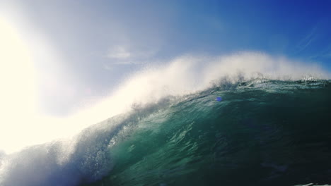 glassy wave breaks in slow motion under sunlight with fluid texture