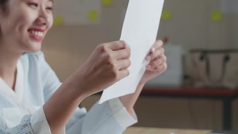 close up of asian woman designer positively shaking her head while looking at the layout bond at the office