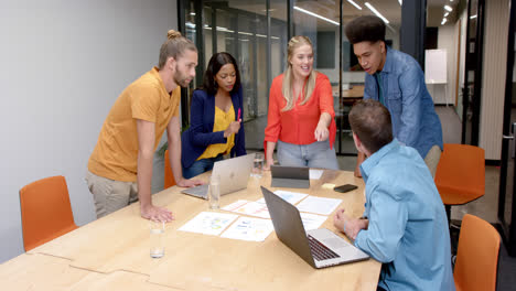 Happy-diverse-colleagues-with-laptops-in-discussion-at-casual-office-meeting,-slow-motion