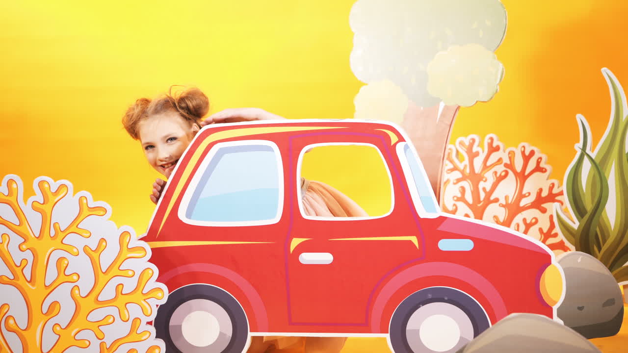 Simpatica bambina su uno sfondo di muro giallo brillante. Una bella bambina gioca con una grande macchina giocattolo.