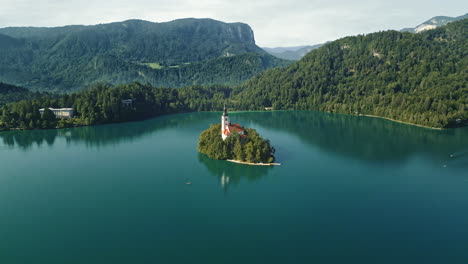 bled island slovenia in calm empty lake reflecting sky, aerial orbit