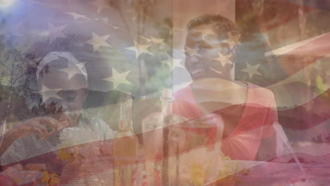 animation of flag of usa over african american mother and daughter eating dinner in garden