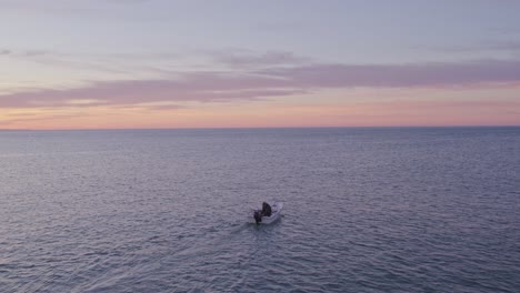 Small-fishing-boat-on-calm-atlantic-ocean-during-sunrise-at-Portugal,-aerial