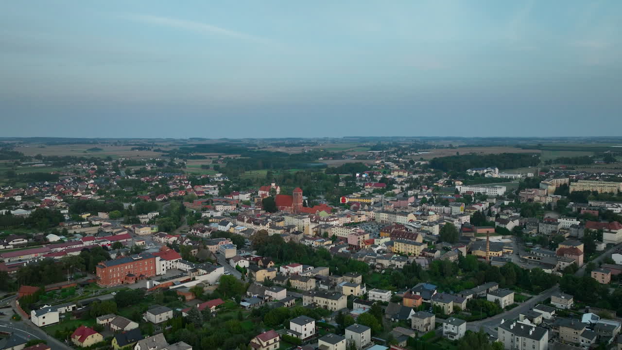폴란드 루바바의 공중 파노라마: 과 숲으로 둘러싸인 주거 지역과 산업 지역이 여있는 도시, 가라앉는 해가 지는 하늘 아래