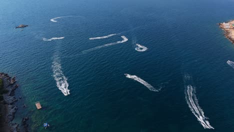 boats creating white trails on the vibrant blue waters off the coast of ksamil, albania, aerial view