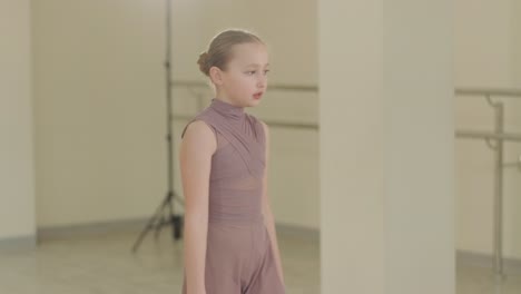 un grupo de jóvenes estudiantes de ballet con ropa de baile negra practicando posiciones en un amplio estudio de ballet con pisos de madera y barras montadas en la pared. expresiones enfocadas y movimientos sincronizados.