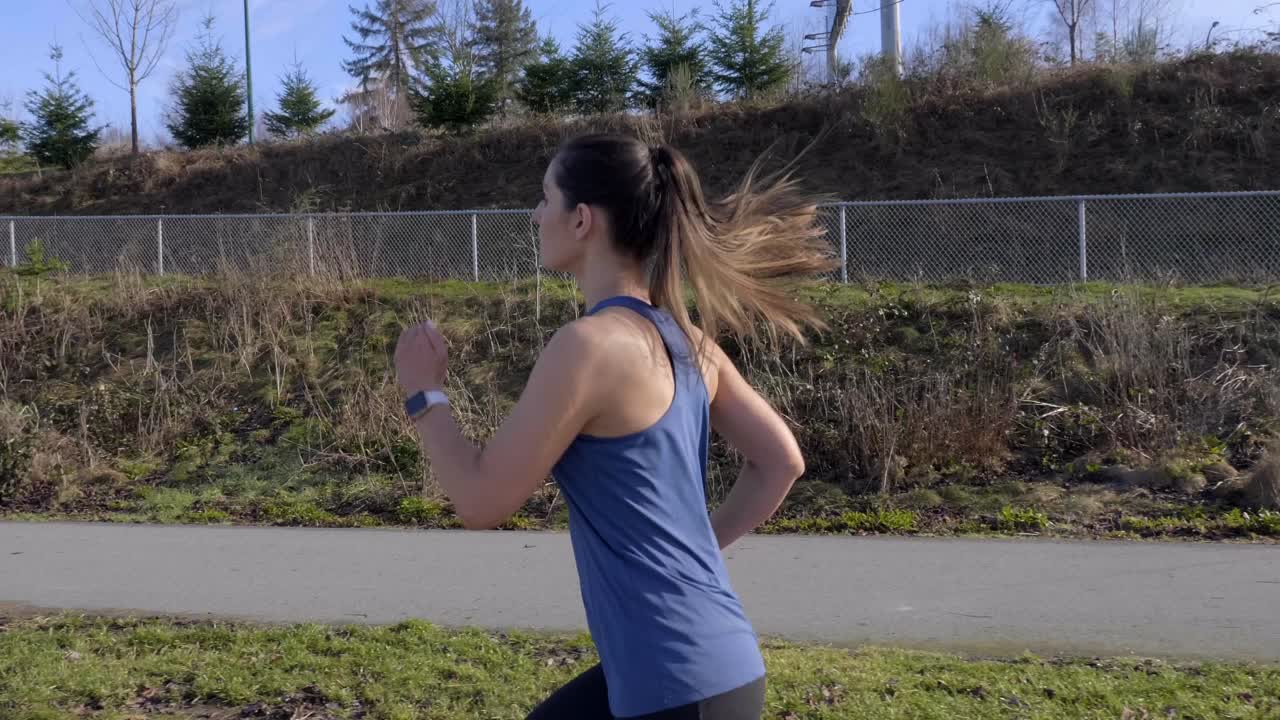 Healthy athletic young woman out running Winter morning tracking shot