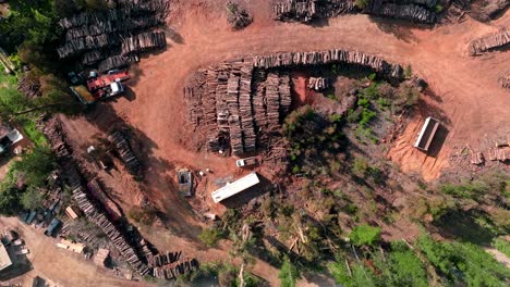 Top-view-dolly-in-aerial-view-of-a-sawmill-with-logs-piled-up-in-stacks-on-a-sunny-day