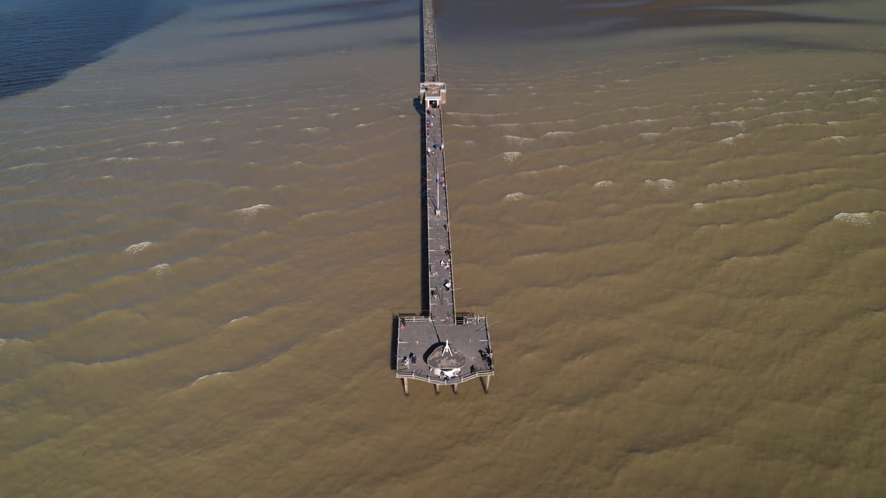 fotografía aérea reveladora de turistas caminando en el paseo marítimo sobre el río la plata, punta lara, buenos aires, argentina