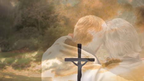 animation of cross and sunset over back view of embracing senior couple