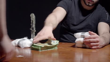 imagen recortada de un hombre intercambiando paquetes de cocaína en polvo con dinero.