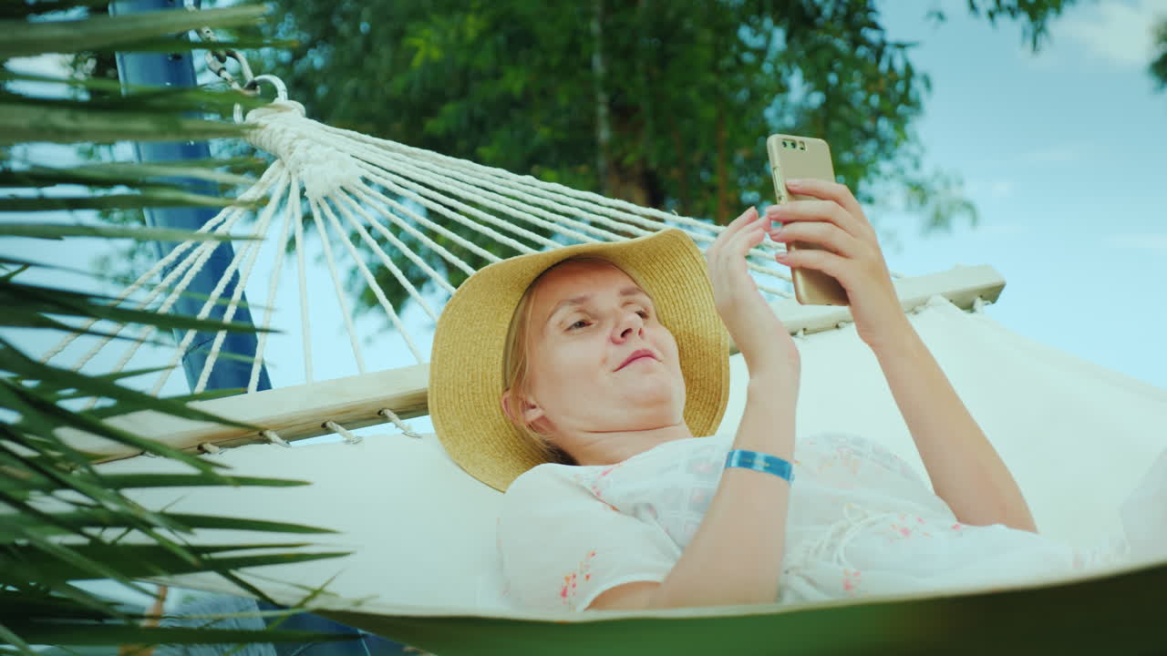 el retrato de una mujer de vacaciones yace en una hamaca usa un video de smartphone 4k