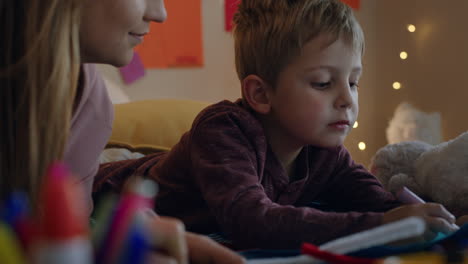 niño pequeño haciendo invitaciones para la fiesta de cumpleaños con la madre ayudando al hijo en el dormitorio colorido disfrutando de la imaginación creativa
