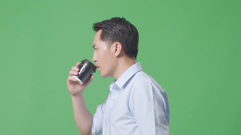 side view close up of asian business man walking and drinking coffee on green screen background in the studio