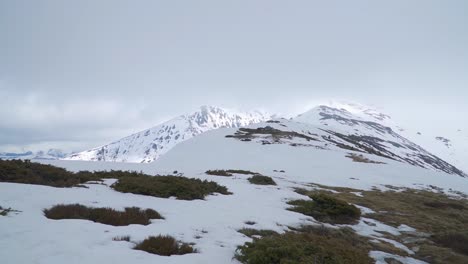 Las-Laderas-Cubiertas-De-Hierba-Se-Convierten-En-Picos-Montañosos-Cubiertos-De-Nieve-En-La-Distancia