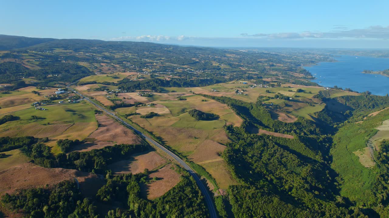 Tomada aérea da Ilha de Chiloé no Chile com paisagens exuberantes e vista costeira, sob a luz do sol.