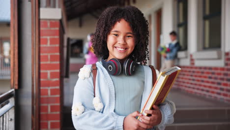 portrait of a smiling student with books and headphones at school
