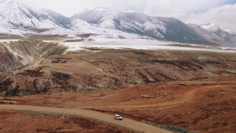 thrilling drone shot: jeep speeds through desert road of korala border at  lomanthang, upper mustang, nepal. majestic mountain ranges and open plains ignite wanderlust. perfect for adventure-seekers.