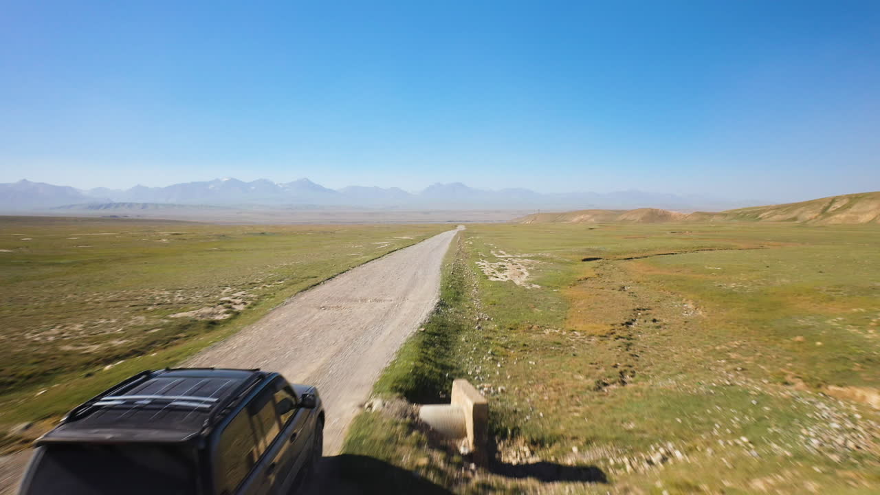 filmación cinematográfica de drones siguiendo a un todoterreno a lo largo de la carretera cerca de kel-suu en kirguistán