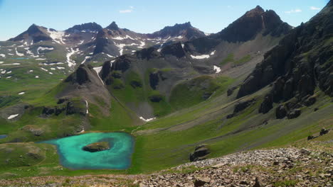 Aéreo-Cinematográfico-Vista-Superior-Hielo-Cuenca-Del-Lago-Isla-Silverton-Lago-Agua-Azul-Agua-Clara-Tundra-Alpina-Impresionante-Cordillera-Nieve-Flores-Silvestres-Mediados-De-Verano-Durante-El-Día-Hermosa-Cámara-Lenta-Hacia-La-Izquierda-Movimiento