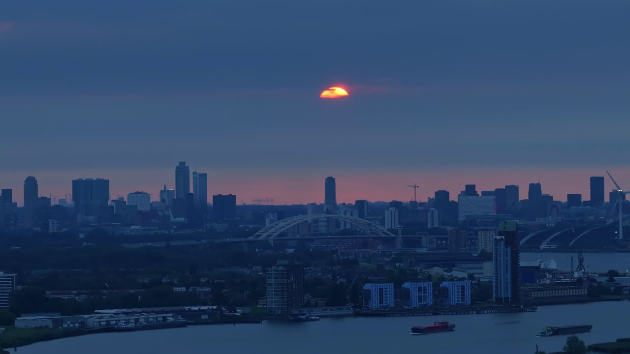 Sunset sky over the city of Rotterdam and river Nieuwe Maas with reds, orange and blues