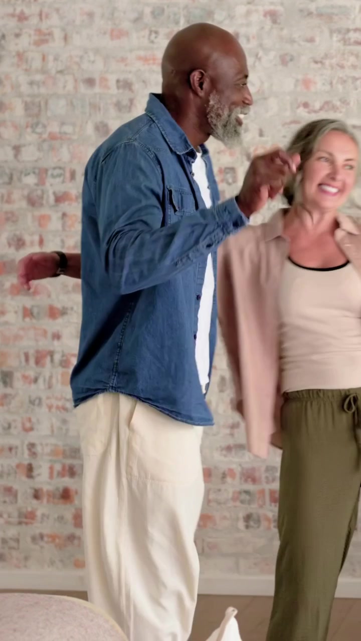 Video verticale: Uomo che entra e accompagna una donna a una sedia nel soggiorno, con un alone animato che indica comfort.