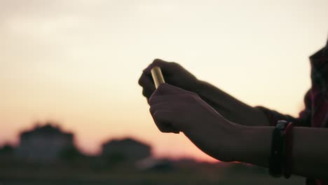 two friends are lighting firework candles and celebrating together during sunset