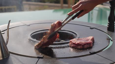 slow motion shot of a chef flipping the steaks to evenly cook on a bbq