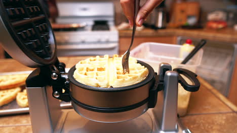 pulling a fresh, hot, golden brown belgian waffle off the iron - isolated slow motion