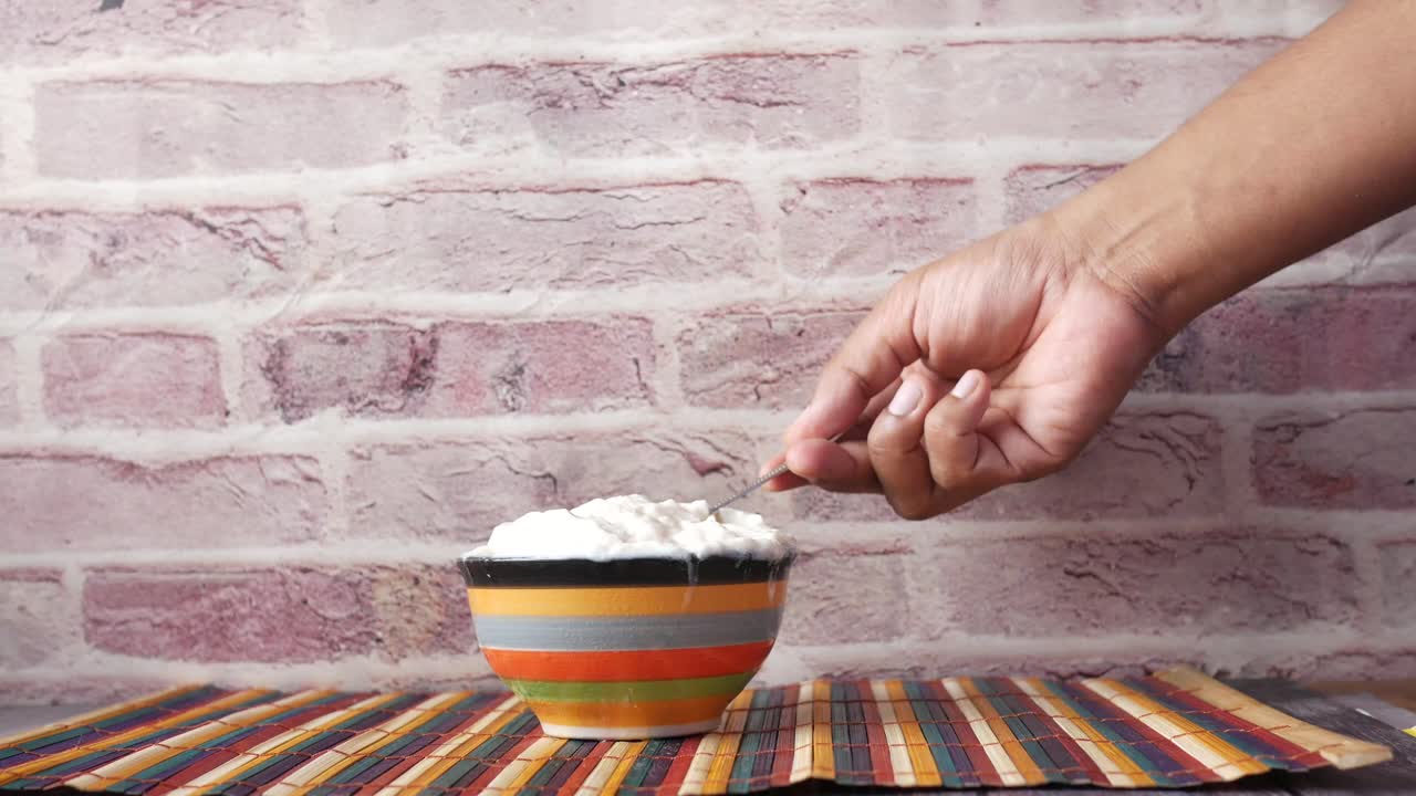 Hand scooping yogurt from a colorful bowl