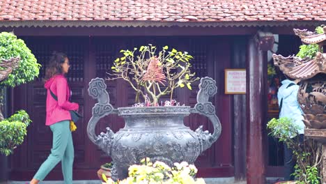 people walking past incense burner in hanoi temple