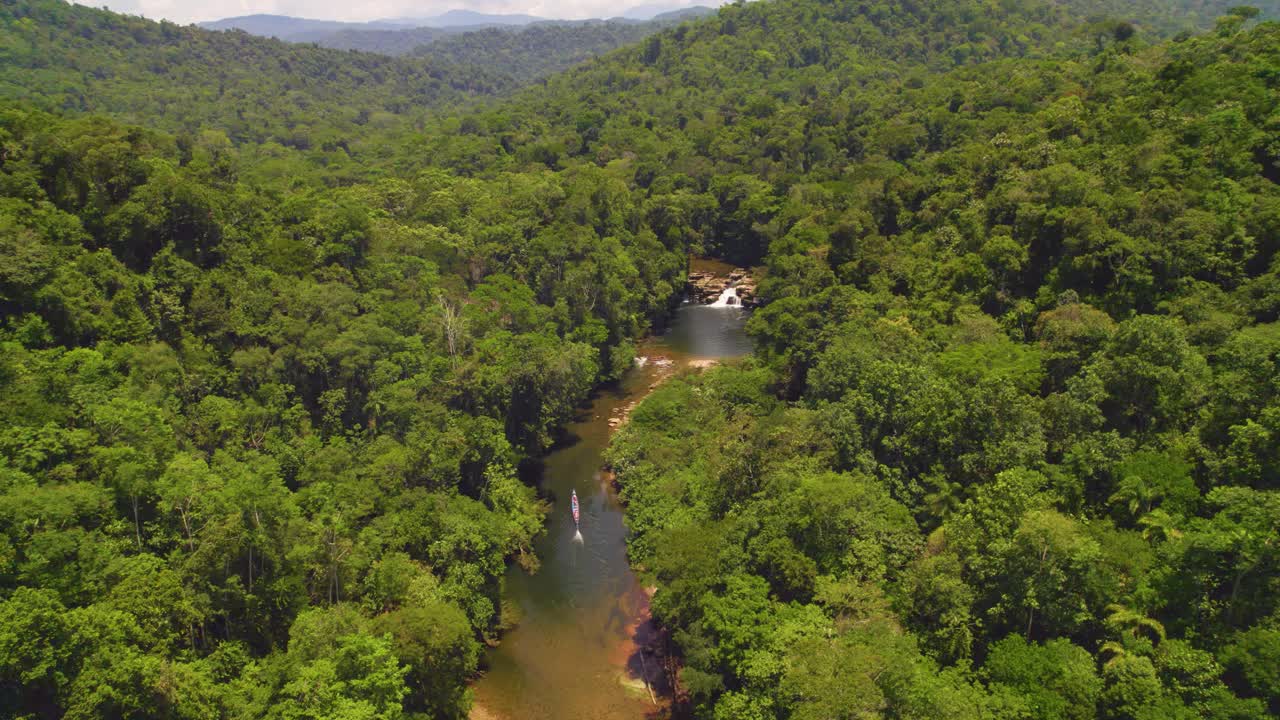 una selva exuberante en oxapampa, perú con un río serpenteando a través y una pequeña cascada, luz del día, vista aérea