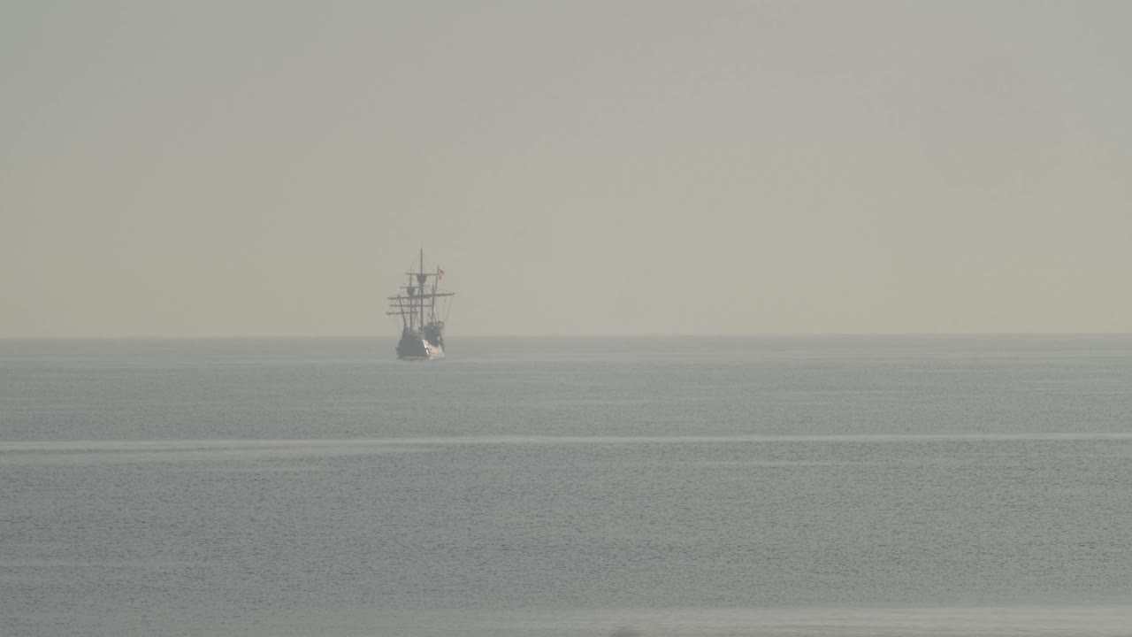 ferdinand magallanes nao victoria carrack réplica de barco con bandera española navega en la distancia en el mediterráneo al amanecer en mar tranquilo en cámara lenta 60fps