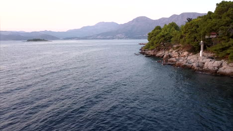 very low and fast footage over sea water pushing in to mountainous hills in croatia, dubrovnik, during sunset