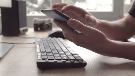 young man using tablet while sitting computer keyboard and mouse. freelancer photographer working and using tablet for communication with clients.