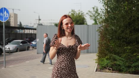 mujer feliz en un vestido floral disfrutando de la calle de la ciudad