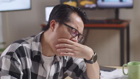 close up of asian male yawning and sleeping while working on a car design sketch on table in the studio