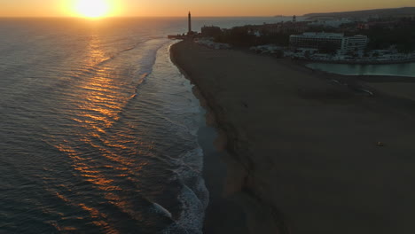 Flug-über-Die-Küste-Des-Strandes-Von-Maspalomas-Bei-Sonnenuntergang-Mit-Dem-Leuchtturm-Von-Maspalomas-Und-Dem-Teich-Im-Hintergrund