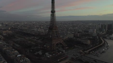 Vista-De-ángulo-Alto-De-La-Costa-Del-Río-Sena-Y-El-Parque-Alrededor-De-La-Torre-Eiffel.-Ciudad-Al-Anochecer-En-Segundo-Plano.-París,-Francia