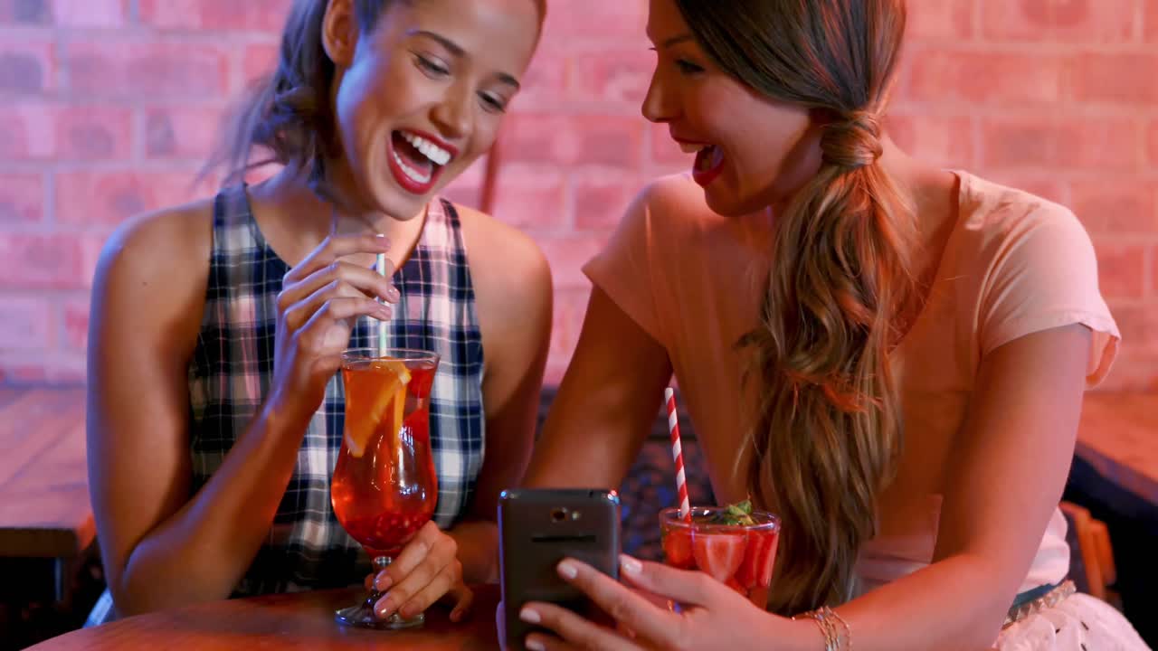 animación de iconos de cerveza sobre felices amigas caucásicas que usan teléfonos inteligentes