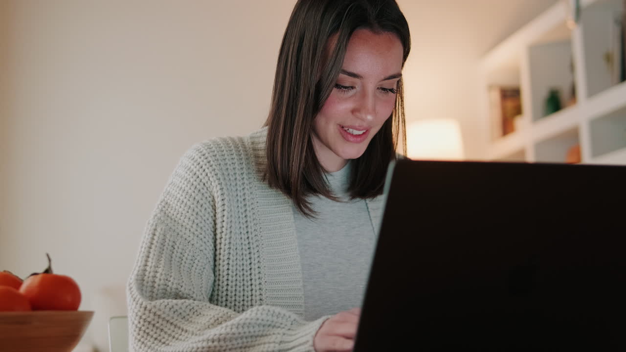 Giovane donna sorridente mentre lavora al computer portatile a casa