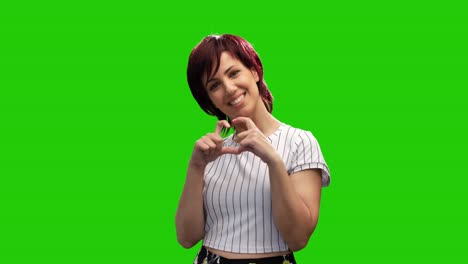 Beautiful-smiling-woman-pose-on-green-screen-and-make-heart-gesture-with-hands