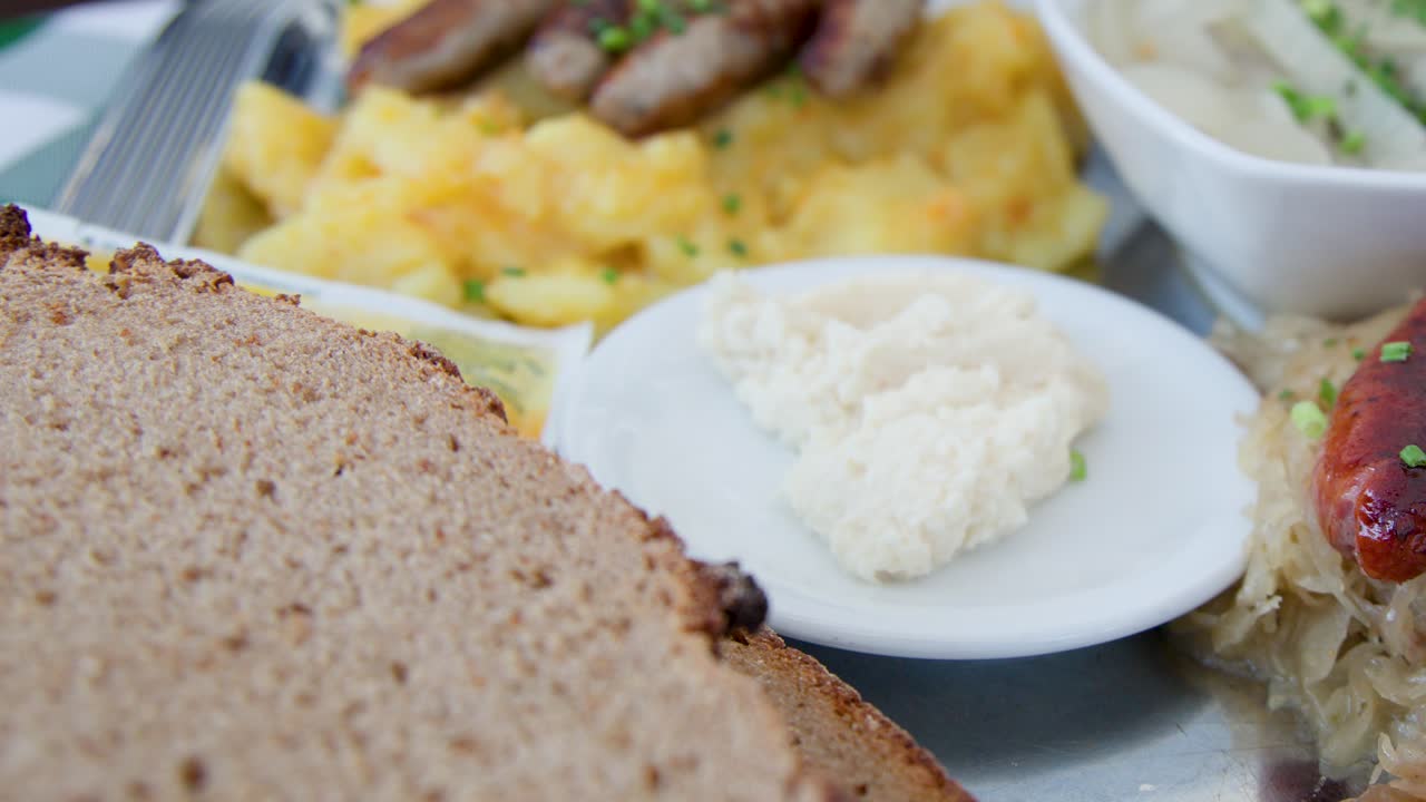 Close-up of assorted German sausages, sauerkraut, potato salad, rye bread, horseradish, natural lighting
